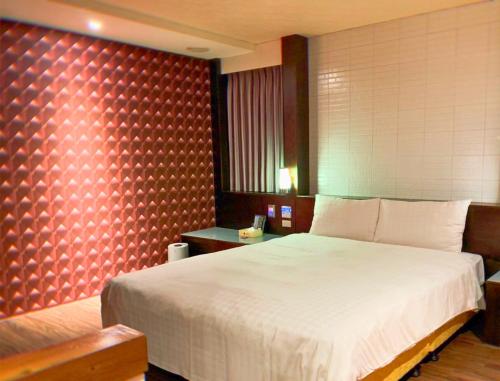 a bedroom with a large bed and a red wall at Langkei Motel in Daxi