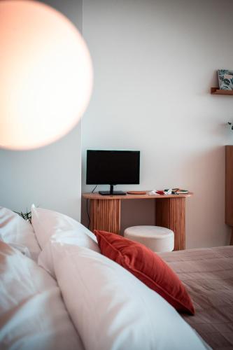 a bed with a red pillow and a desk with a television at Arcu Retreat in Positano