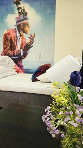 a bed with a painting on the wall and a table with flowers at Orrefors Vandrarhem in Nybro