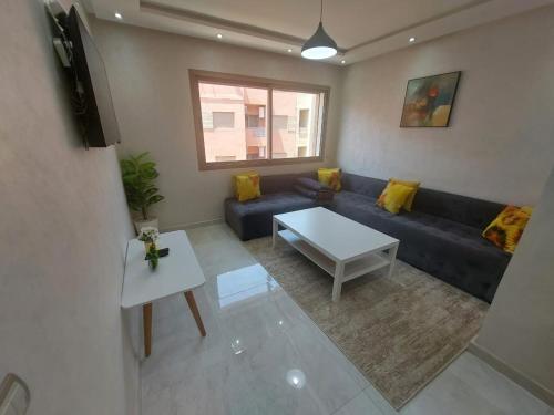 a living room with a blue couch and a table at Appartement centre ville in Oulad Akkou