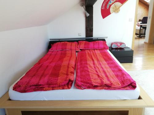 a bed with red blankets on top of it at Großzügige und kunstvolle Dachgeschosswohnung in Leichlingen