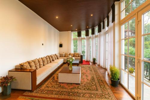 a living room with a large couch and windows at The Ceylon Lodge in Nuwara Eliya