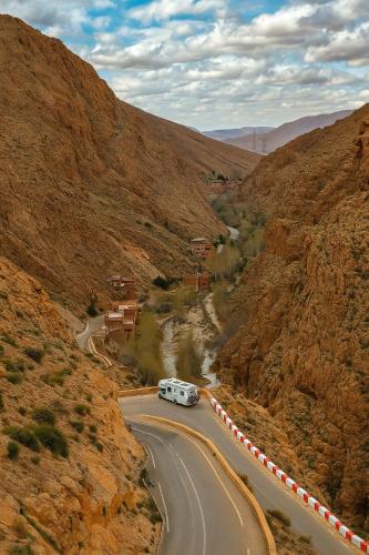 a bus driving down a road in a mountain at Auberge La Fibule Du Dades in Aït Idaïr