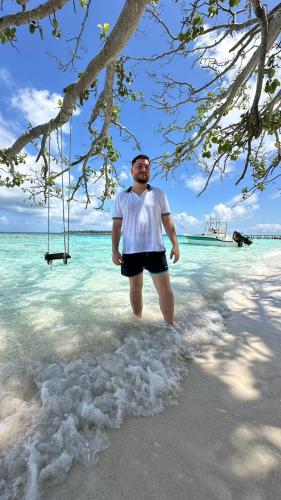 a man standing in the water on a beach at Finimas Residence in Thimarafushi
