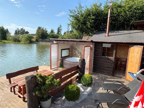 a small cabin with a hot tub on the side of a lake at Chata u Rybníka in Žďár nad Sázavou