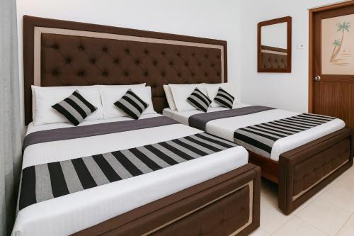 two beds in a hotel room withskirts at The Ceylon Lodge in Nuwara Eliya