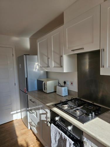 a kitchen with white cabinets and a stove top oven at Large Doubleroom Dartford Central-Close to all amenities in Dartford