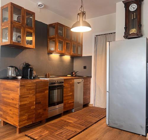 a kitchen with wooden cabinets and a stainless steel refrigerator at Apartament Ogrodowa Józefosław in Józefosław