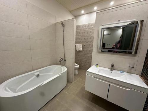 a white bathroom with a tub and a sink at Majestic Family Lodges in Islamabad