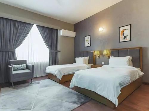 a hotel room with two beds and a chair at Majestic Family Lodges in Islamabad