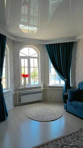 a living room with a blue couch and windows at Guest House Bektash in Kyzart