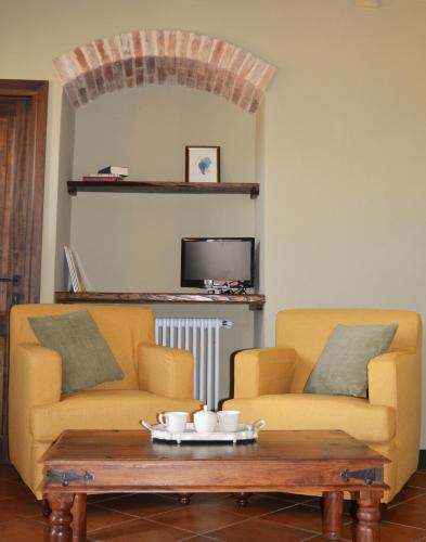 a living room with two yellow couches and a coffee table at Borgo dé Brandi in Monteriggioni