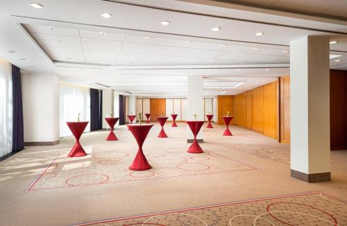 a row of red tables in a large room at Leonardo Hotel Weimar in Weimar