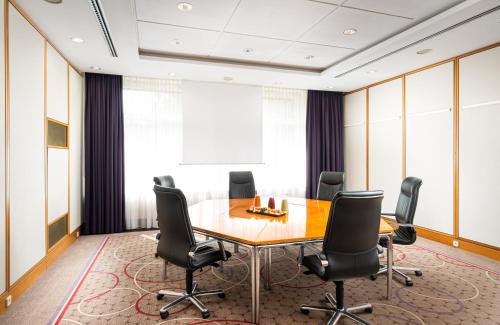 an office meeting room with a wooden table and black chairs at Leonardo Hotel Weimar in Weimar
