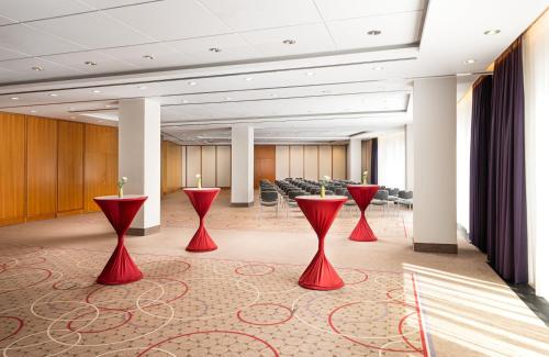 a conference room with red tables and chairs at Leonardo Hotel Weimar in Weimar