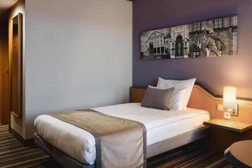 a hotel room with a bed and a picture on the wall at Leonardo Hotel Weimar in Weimar