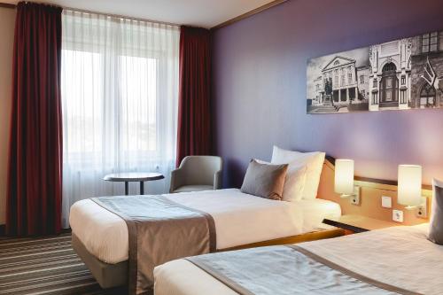 a hotel room with two beds and a table at Leonardo Hotel Weimar in Weimar