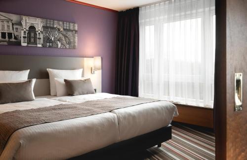 a bedroom with a large bed and a window at Leonardo Hotel Weimar in Weimar