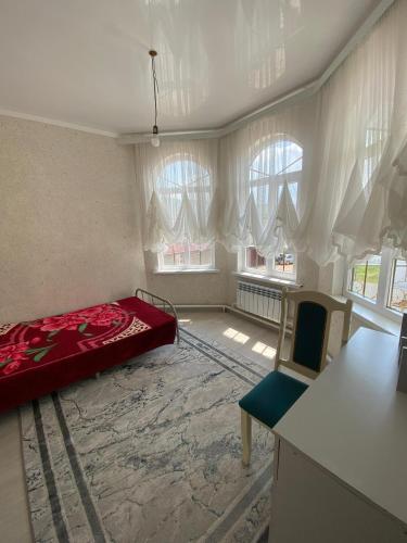 a bedroom with a bed and a table and two windows at Guest House Bektash in Kyzart