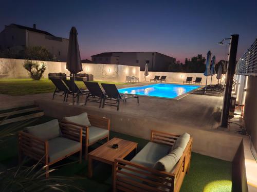 a patio with chairs and a swimming pool at night at LUCY Apartments with heated saltwater pool and free private parking in Zadar