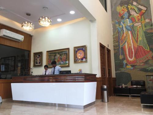 two people standing at a counter in a lobby at Hotel Kridha Residency - Opposite Prem Mandir Vrindavan in Mathura