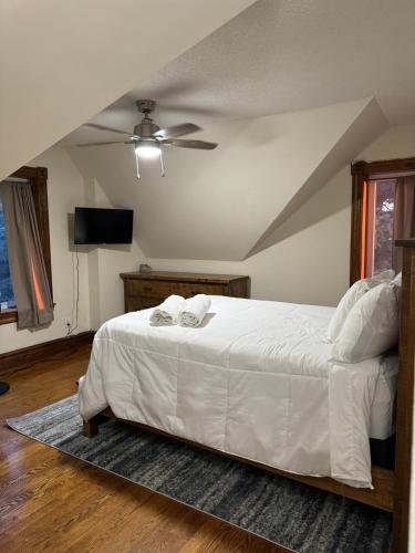 a bedroom with a white bed with a ceiling fan at Farmhouse Resort in Midhurst
