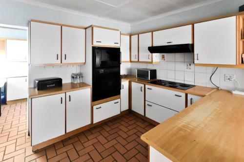 a kitchen with white cabinets and a black refrigerator at Home in Beacon Bay in East London