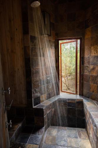 a bathroom with a stone shower with a window at Forest Song in Plettenberg Bay
