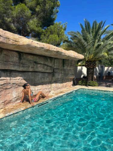 a woman sitting on the side of a swimming pool at Apartamentos Montgò in Denia