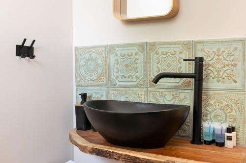 La salle de bains est pourvue d'un lavabo noir sur un comptoir en bois. dans l'établissement בקתת המפל, à Eli Ad