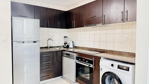 a kitchen with brown cabinets and a washer and dryer at JBR Studio Apartment - Bay Central in Dubai