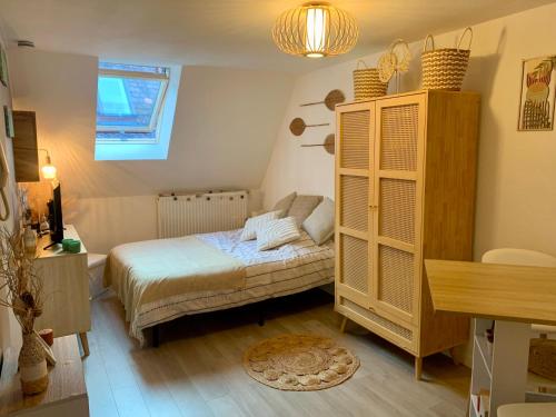 a bedroom with a bed and a wooden cabinet at Le nid du Piémont in Barr
