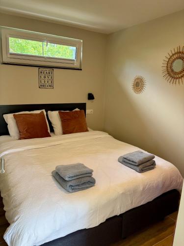 a bedroom with a bed with towels on it at Oosterschelde Lodge met veel privacy en dicht bij het water in Scherpenisse