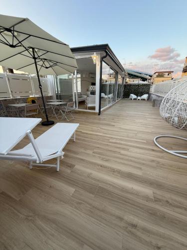 a deck with chairs and an umbrella on a building at Dimora Luminè in Naples
