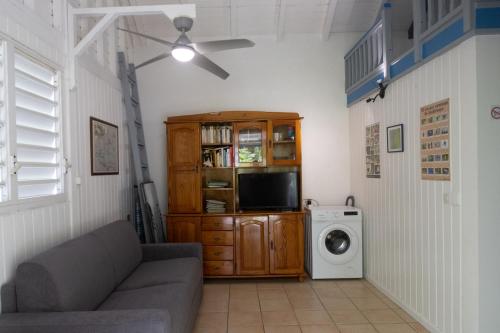 a living room with a couch and a washing machine at Gite le colibri Bungalow Azur avec réserve d'eau in Saint-François
