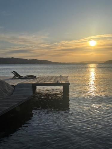 a dock on a body of water with the sunset at Sun, light and sea in Porto Rafael in Porto Rafael