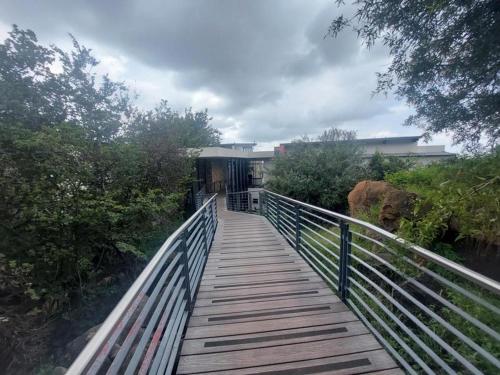 a wooden walkway leading to a building on a bridge at 13 Sunningdale - Jackals Creek Golf Estate in Roodepoort