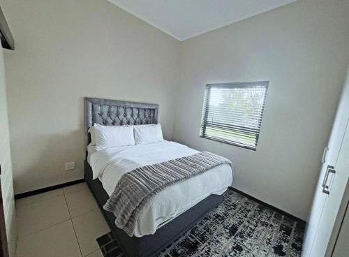a bedroom with a large bed with a window at 13 Sunningdale - Jackals Creek Golf Estate in Roodepoort