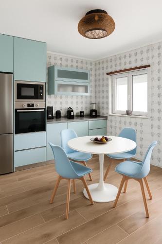 a kitchen with a white table and blue chairs at Paraíso no Furadouro, T2 a apenas alguns passos da praia in Ovar