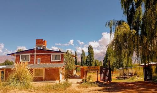 a house with a tree and a fence in front of it at Casas de montañas in Uspallata