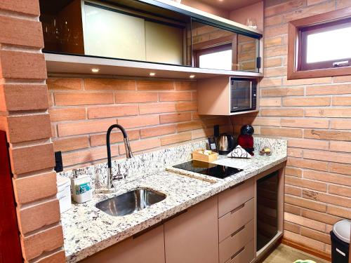 - une cuisine avec un évier et un mur en briques dans l'établissement Mirador da Montanha, à Praia Grande