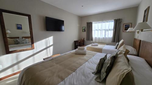 a bedroom with a large bed and a mirror at Cumbres Nevadas - Hostería Boutique in El Chalten