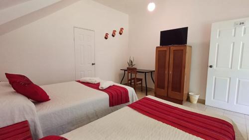 a bedroom with two beds and a tv on the wall at Hotel El Recreo Lanquín-Champey in Lanquín