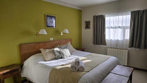 a bedroom with a bed with two towels on it at Cumbres Nevadas - Hostería Boutique in El Chalten