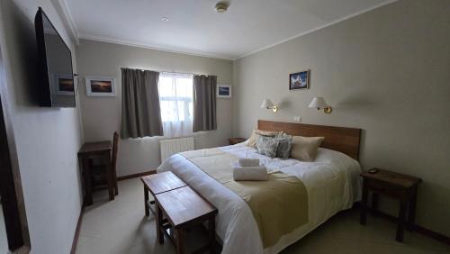 a bedroom with a large bed and a table at Cumbres Nevadas - Hostería Boutique in El Chalten