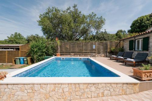 a swimming pool in a yard with a patio and a house at Villa Lilly in Višnjan