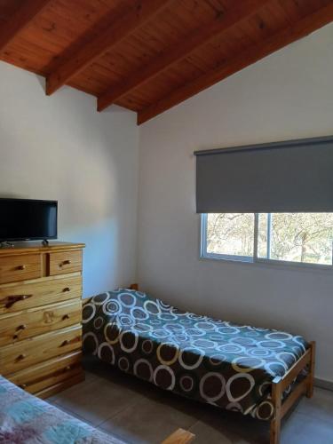 a bedroom with a bed and a dresser and a window at La Porteña in Cortaderas
