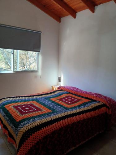 a bedroom with a bed with a colorful blanket on it at La Porteña in Cortaderas