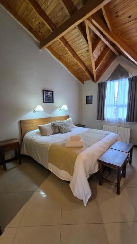 a bedroom with a large bed and a wooden ceiling at Cumbres Nevadas - Hostería Boutique in El Chalten