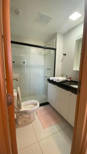 a bathroom with a toilet and a glass shower at Flat em muro alto in Ipojuca